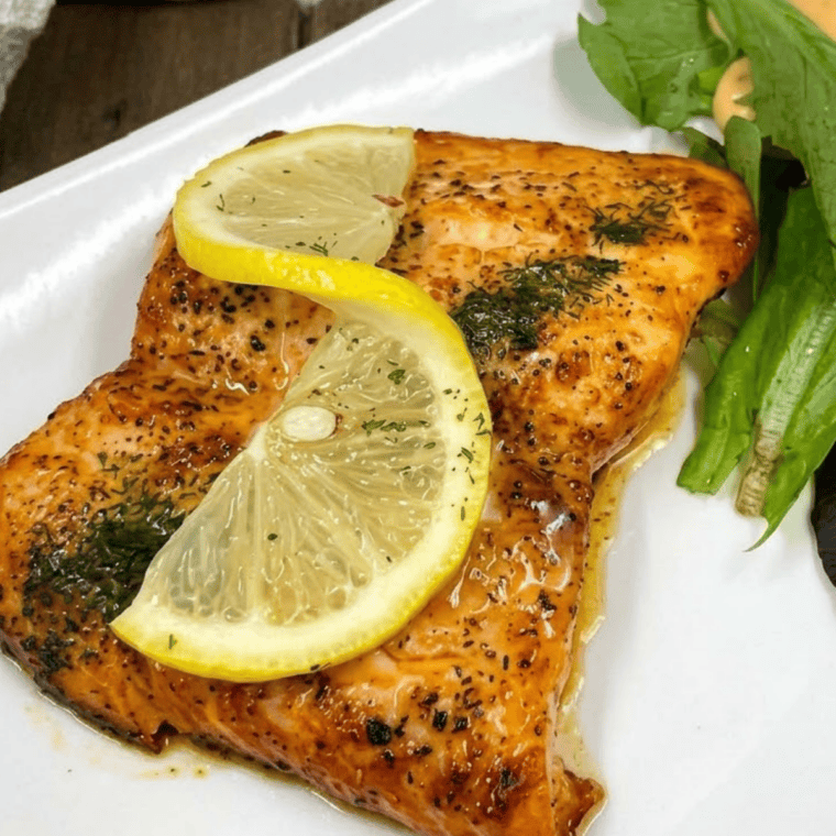 Air fryer honey lemon salmon fillets topped with fresh lemon slices on a white plate