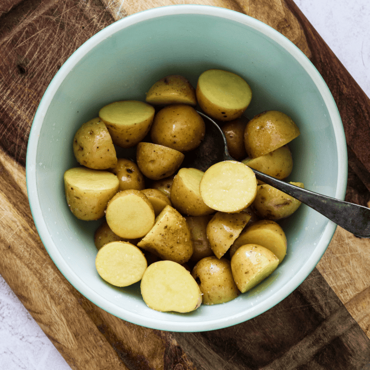 Cut potato chunks being patted dry with a kitchen towel