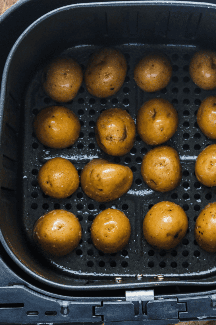Seasoned potato chunks in a single layer in the air fryer basket before cooking