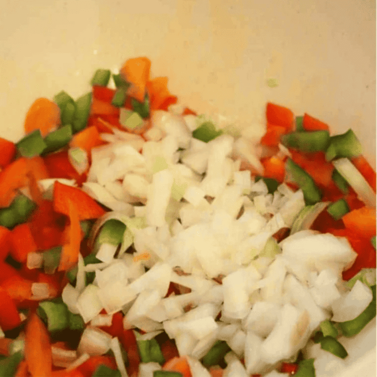 Diced onion and bell pepper sautéing in a skillet for air fryer frittata