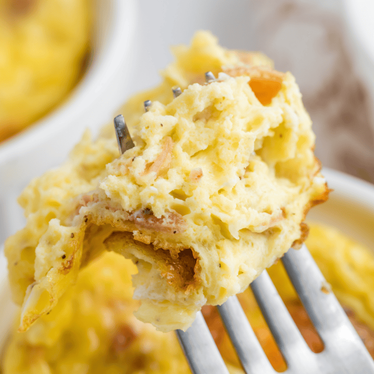 Fluffy air fryer mug omelet with melted cheddar cheese and scallions in a white ramekin