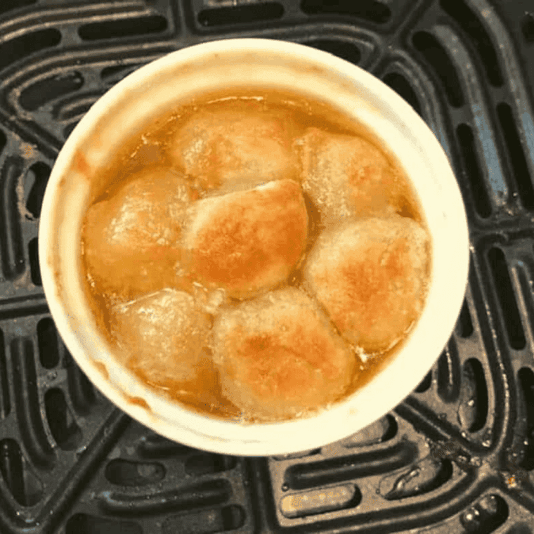 Ramekin with monkey bread cooking in air fryer at 330&deg;F, golden and bubbling