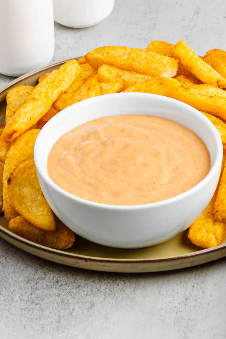 Plate of crispy French fries with a side of homemade Cane’s dipping sauce