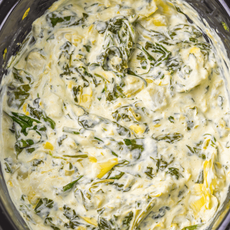Close-up of warm copycat Olive Garden spinach artichoke dip topped with a golden, broiled cheese layer.