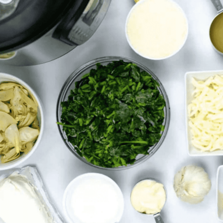 
Ingredients for Instant Pot copycat Olive Garden spinach artichoke dip, including spinach, artichokes, cream cheese, Parmesan, and mozzarella, arranged on a counter.