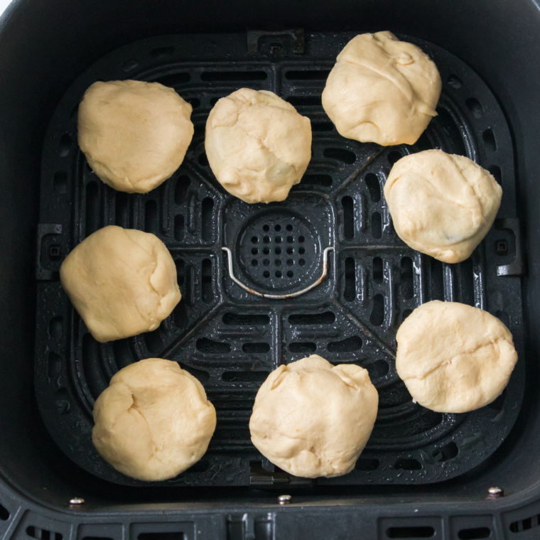 The air fryer is preheated to 350&deg;F and the basket is lined or sprayed to prevent sticking. Preheating helps the dough set quickly once it hits the hot air, locking in the shape.