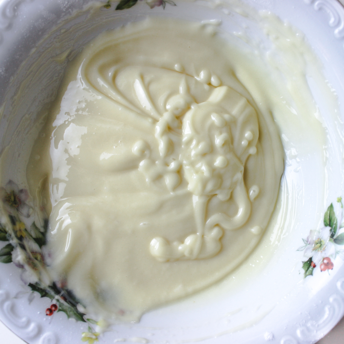 Orange cream cheese frosting beaten smooth in a glass mixing bowl