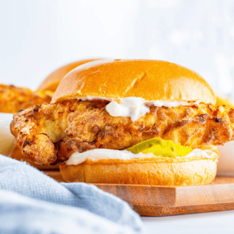 Assembled Air Fryer Popeyes-style chicken sandwich with mayo, pickles, and a golden crispy chicken breast on a brioche bun.