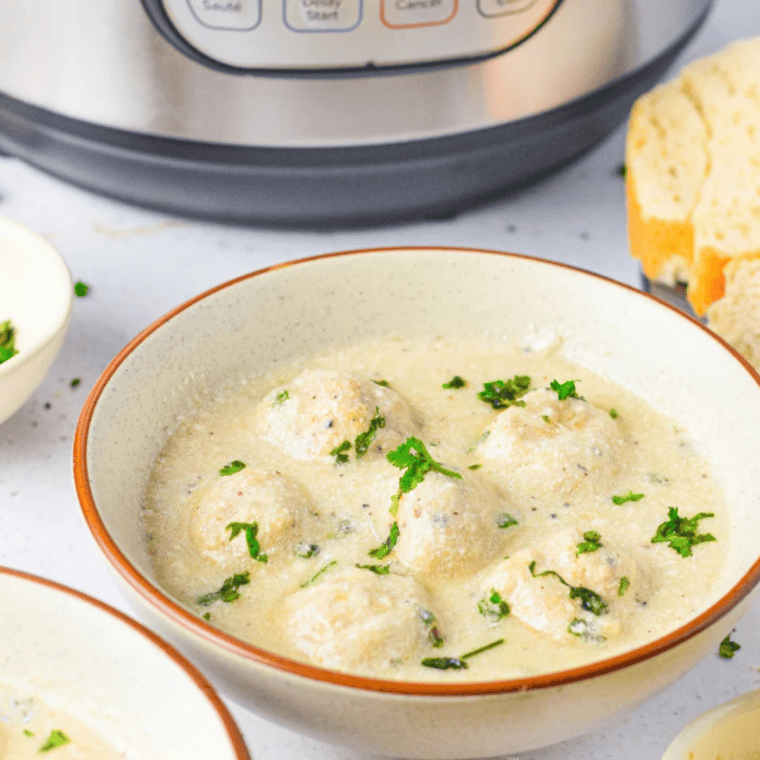 Creamy Alfredo meatballs in a white sauce served over pasta with parsley and parmesan.