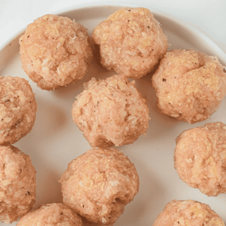 Scoop and shape Raw meatballs portioned with a cookie scoop and rolled on a tray