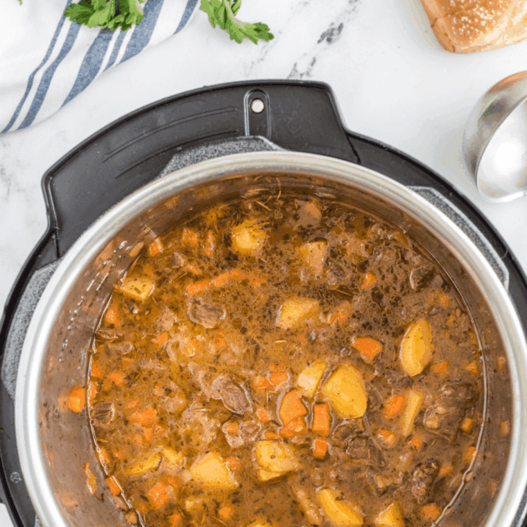 Beef stew ingredients including broth, beer, Worcestershire, soy sauce, brown sugar, garlic, and herbs mixed with carrots, potatoes, and onions in an Instant Pot, ready for high-pressure cooking.