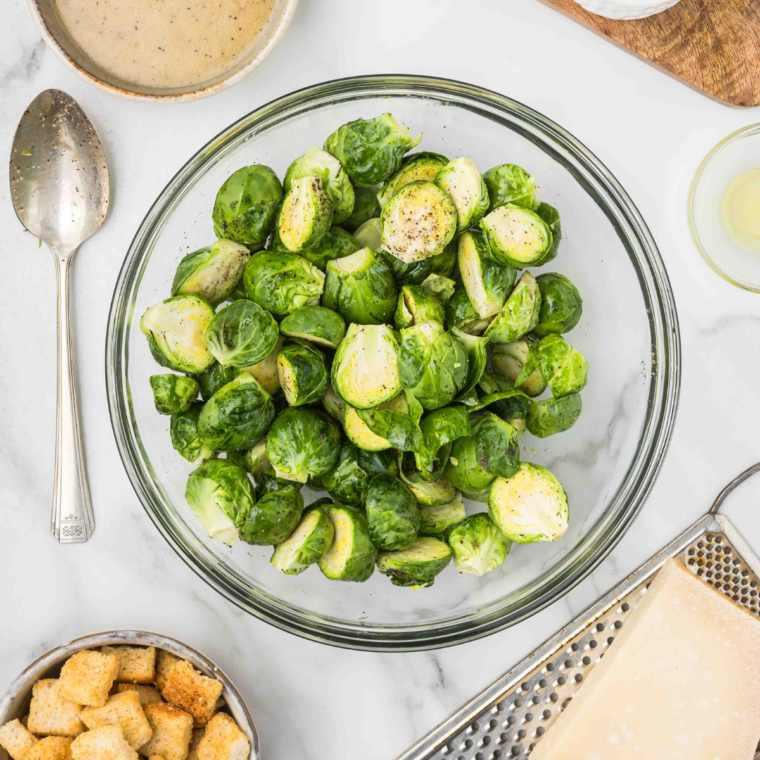 Halved Brussels sprouts tossed with olive oil, salt, and pepper in a large mixing bowl