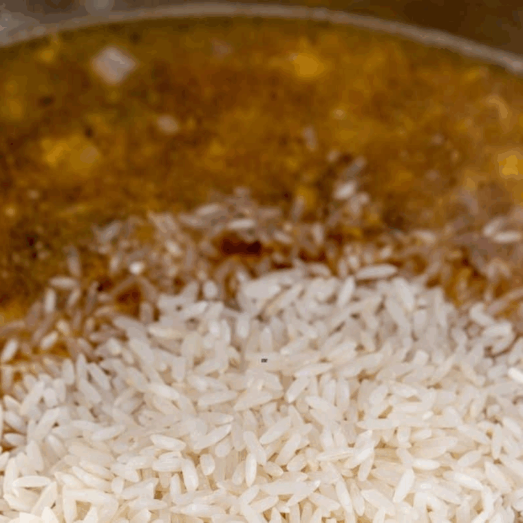 Pouring Basmati rice, chicken broth, and soy sauce into Instant Pot and stirring