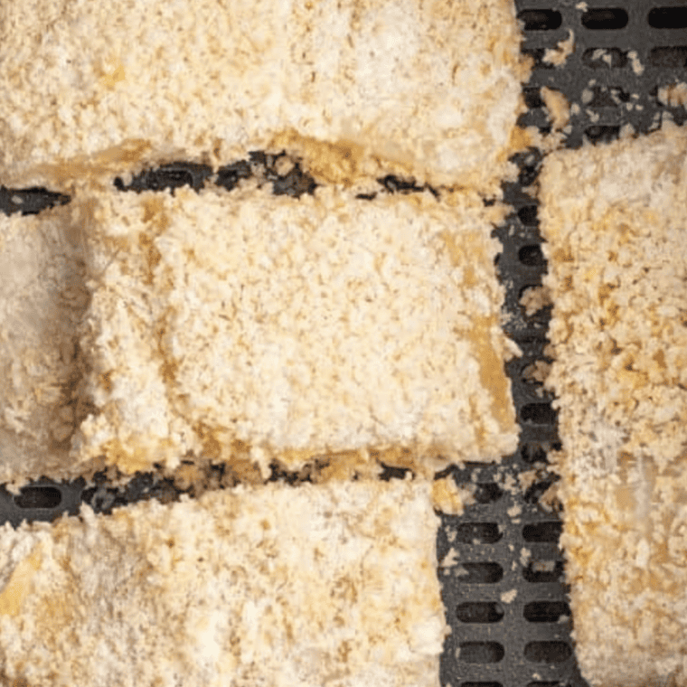 Salmon fillet being pressed into panko breadcrumb and parmesan coating