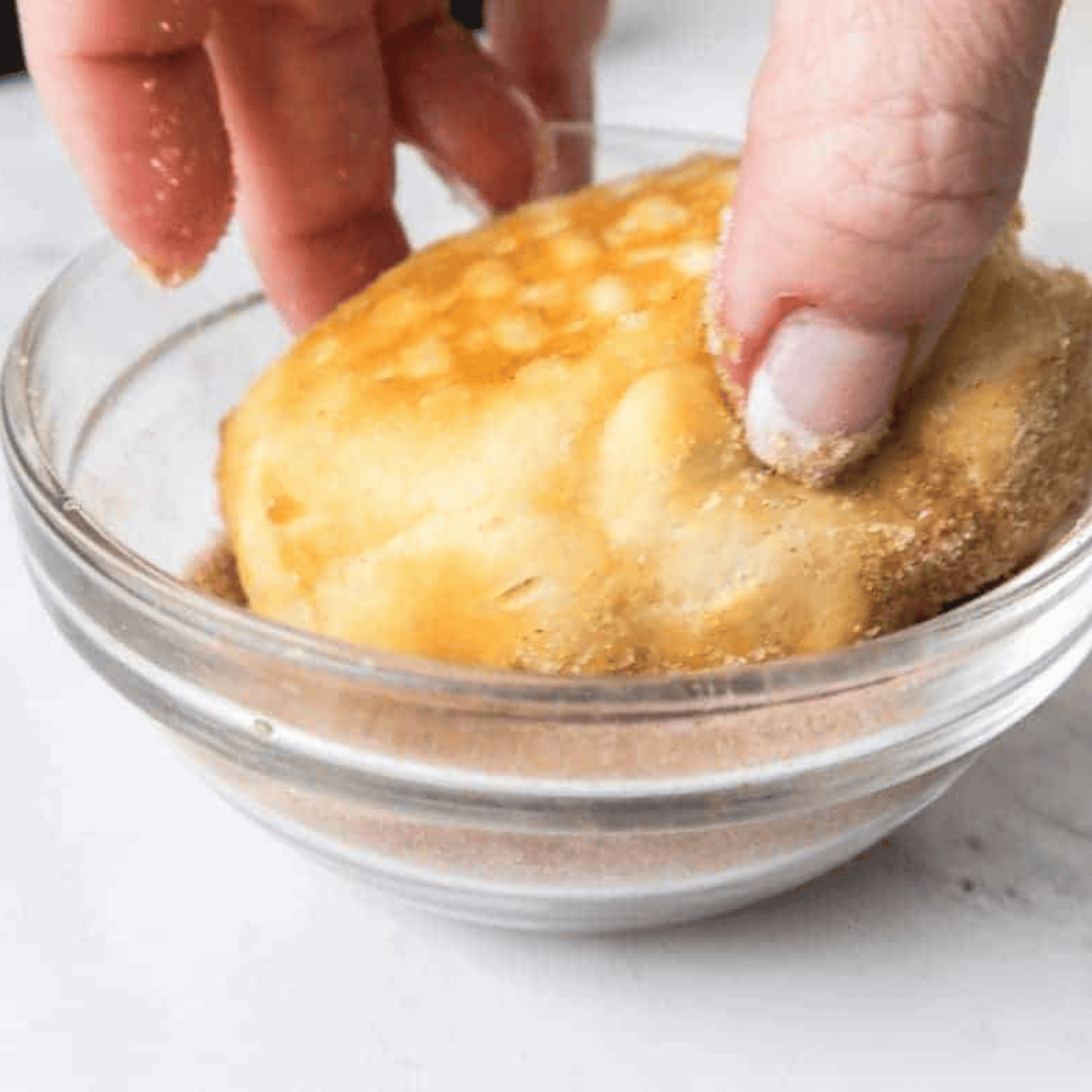 Cinnamon and sugar mixed in a bowl beside melted butter.