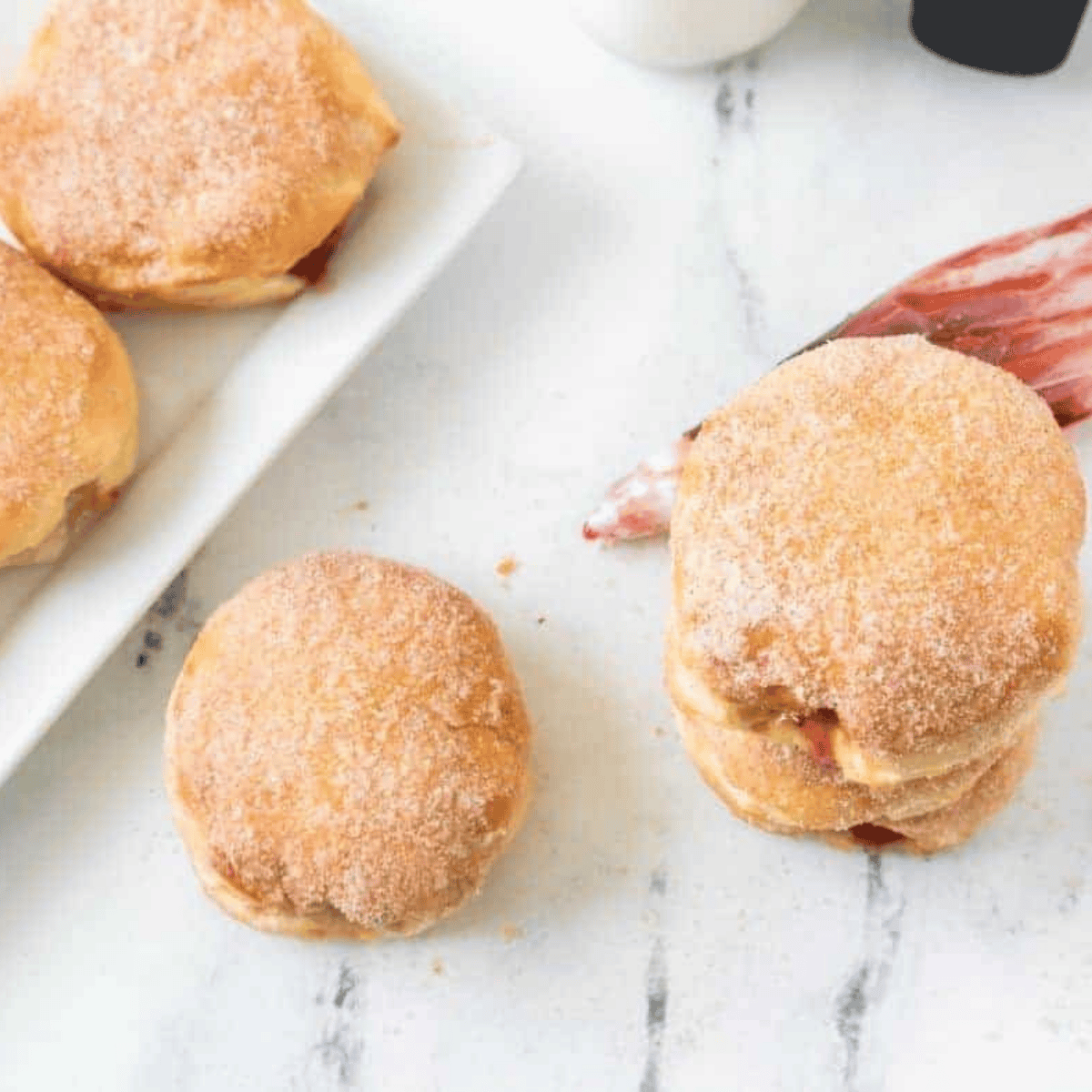 Side view of stacked air fryer jelly donuts showing strawberry filling and cinnamon-sugar coating