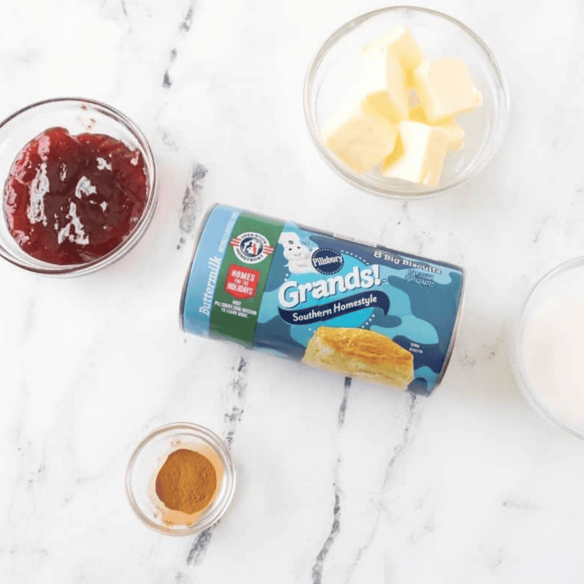 Ingredients for air fryer jelly donuts: canned biscuits, strawberry jam, butter, sugar, cinnamon.