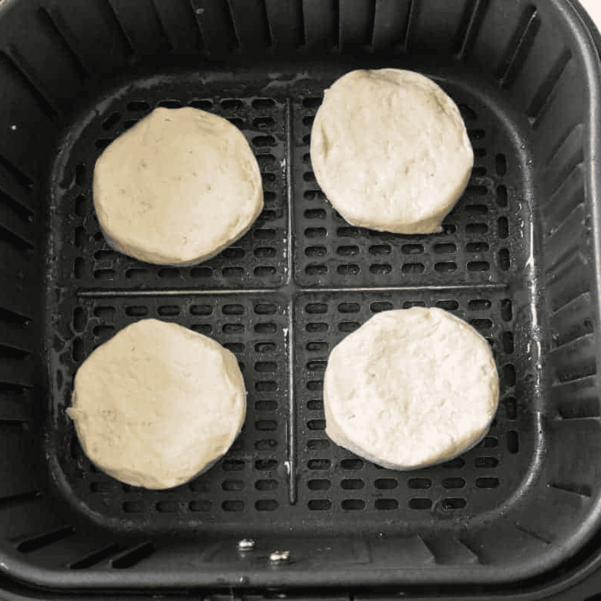 Raw biscuits arranged in an air fryer basket.