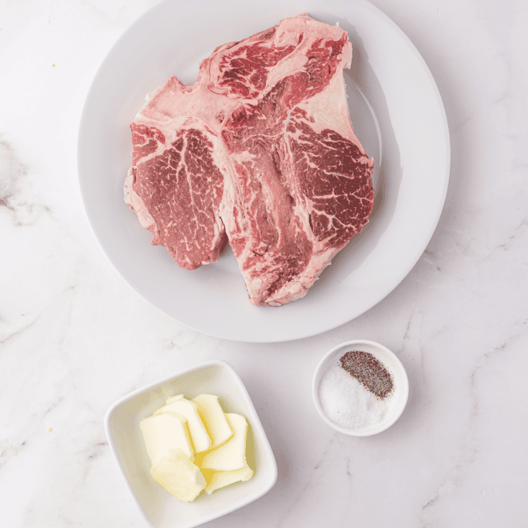 Ingredients for air fryer porterhouse steak: two raw steaks, butter, kosher salt, and black pepper