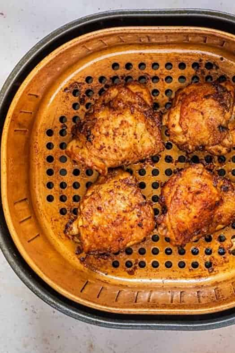 Seasoned turkey thighs skin-side down in an air fryer basket
