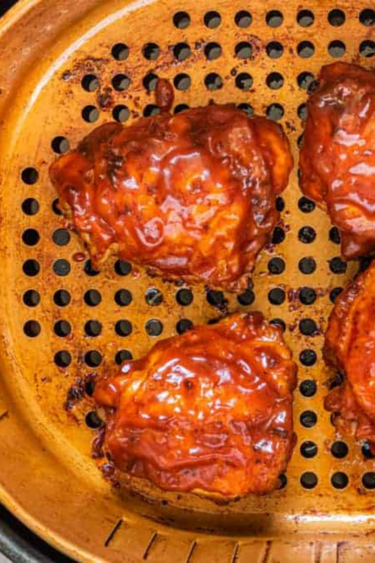 Turkey thighs flipped skin-side up in the air fryer, starting to brown