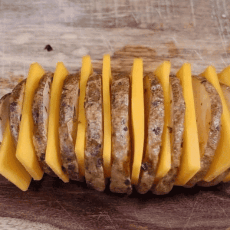 Inserting slices of cheese into Hasselback potato cuts for a gooey, melty filling