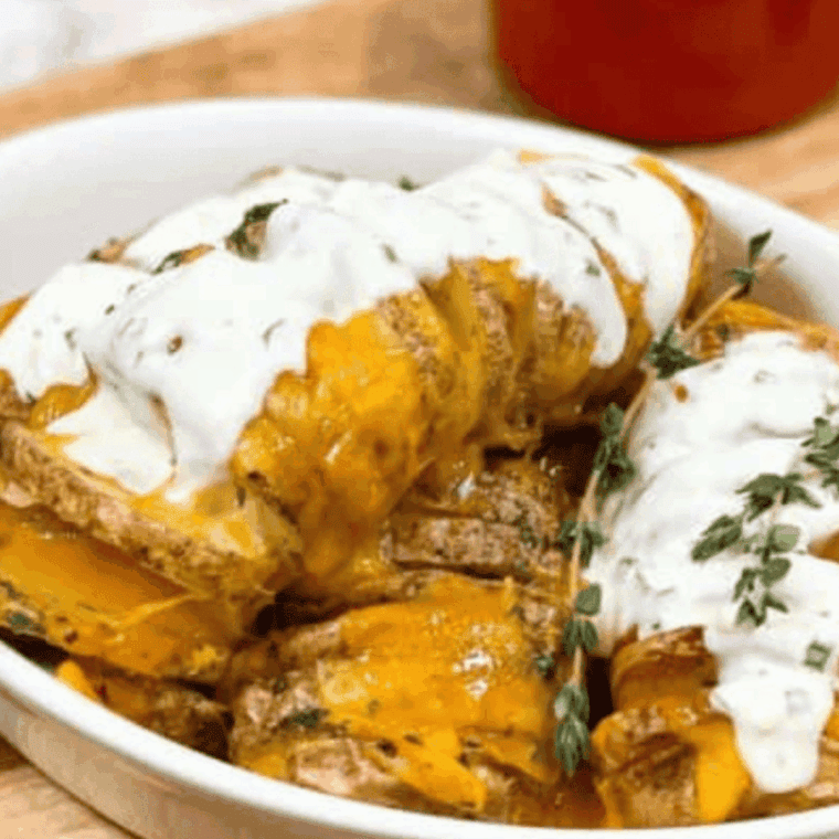 Golden Hasselback potatoes cooked in an air fryer, stuffed with melted cheese and garnished with fresh herbs