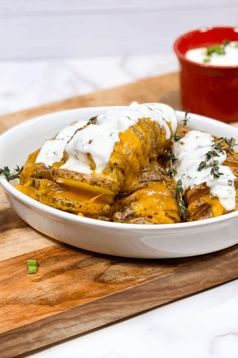 Golden Hasselback potatoes cooked in an air fryer, stuffed with melted cheese and garnished with fresh herbs