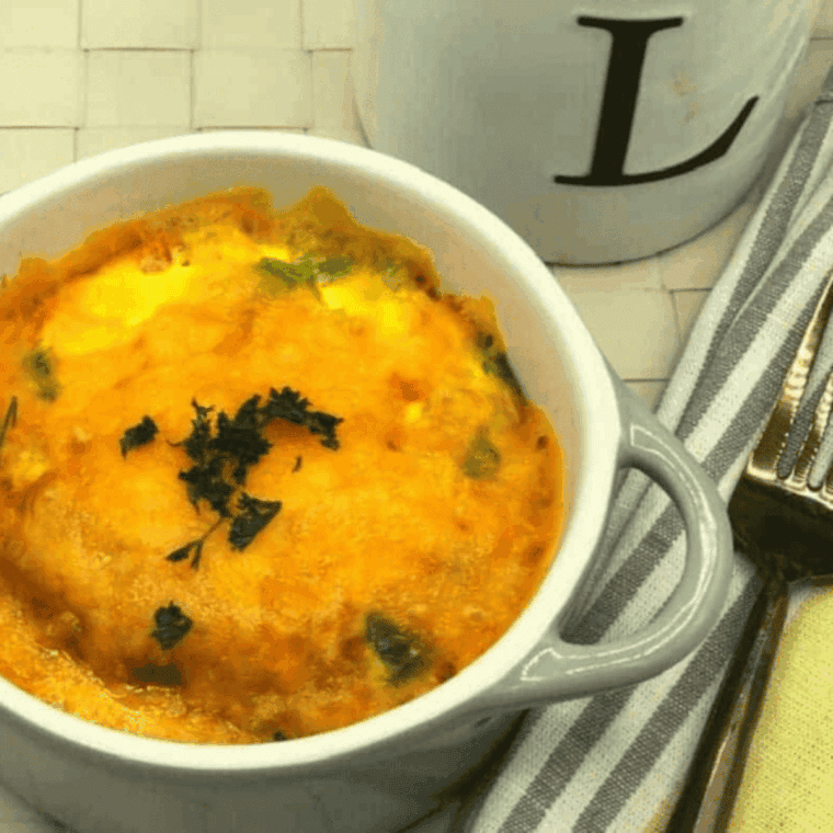 Fluffy air fryer vegetable omelet with bell peppers, onions, and melted cheddar cheese cooked in a small dish.