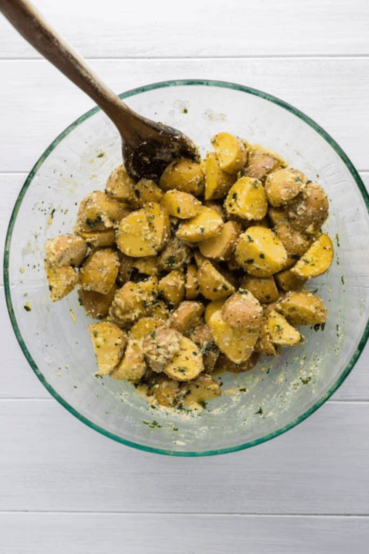 Mixing potatoes with truffle oil, minced garlic, olive oil, truffle salt, sea salt, Parmesan, and black pepper in a large bowl