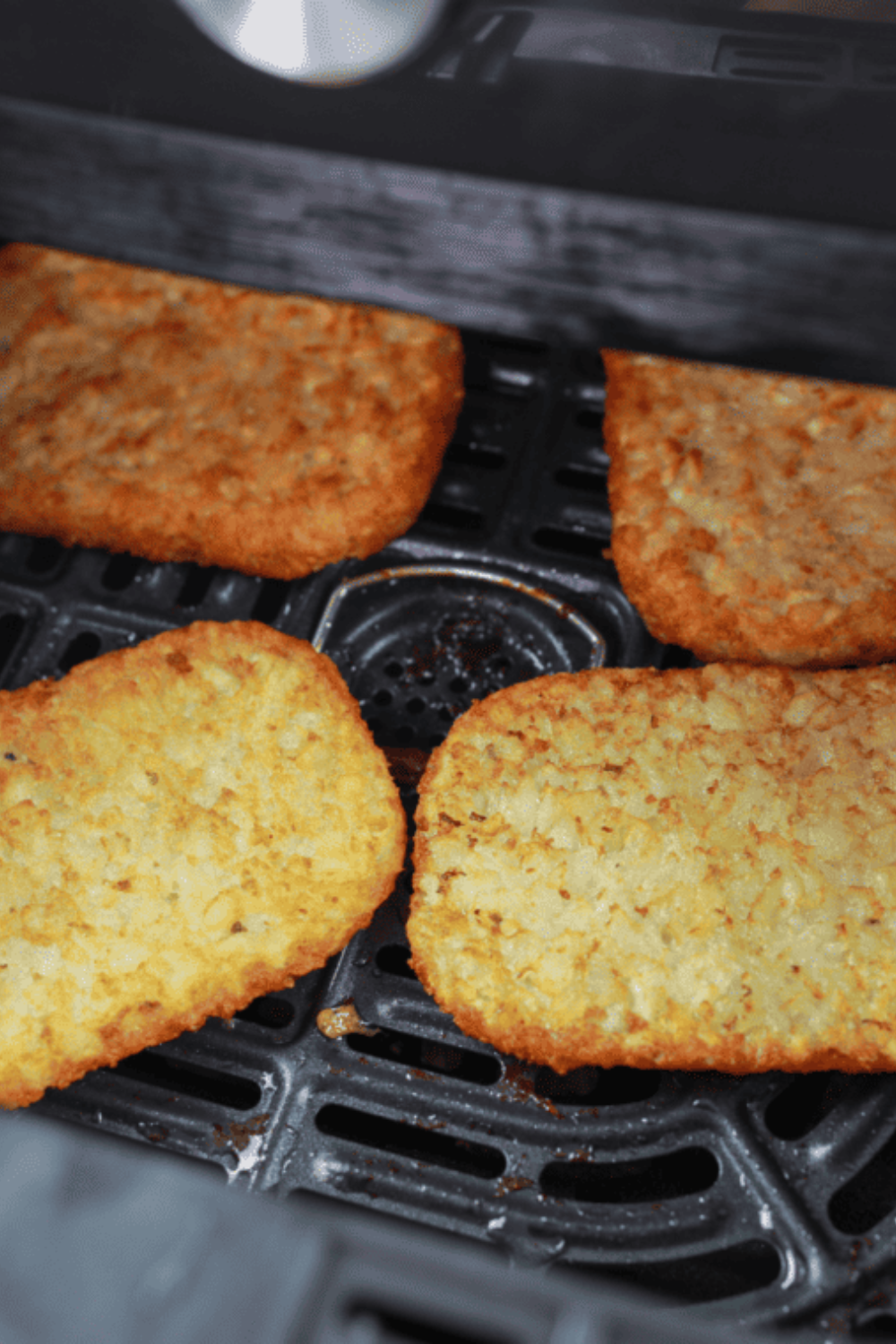 Flipping frozen hash brown patties halfway through air frying to ensure both sides cook evenly until deep golden brown with crispy edges