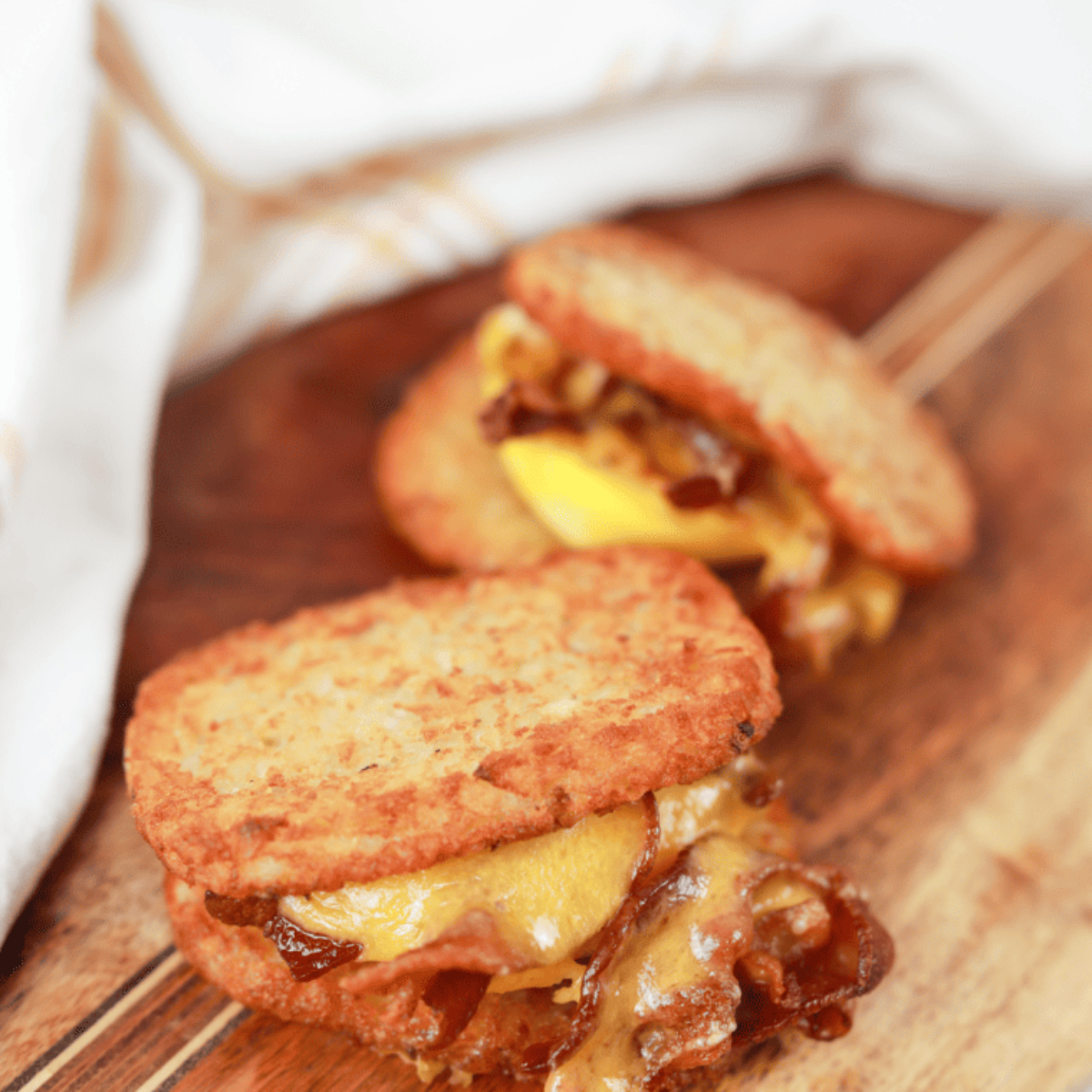 Air fryer hash brown patties resting on a plate for two minutes to finish crisping before serving hot with toppings or dipping sauces