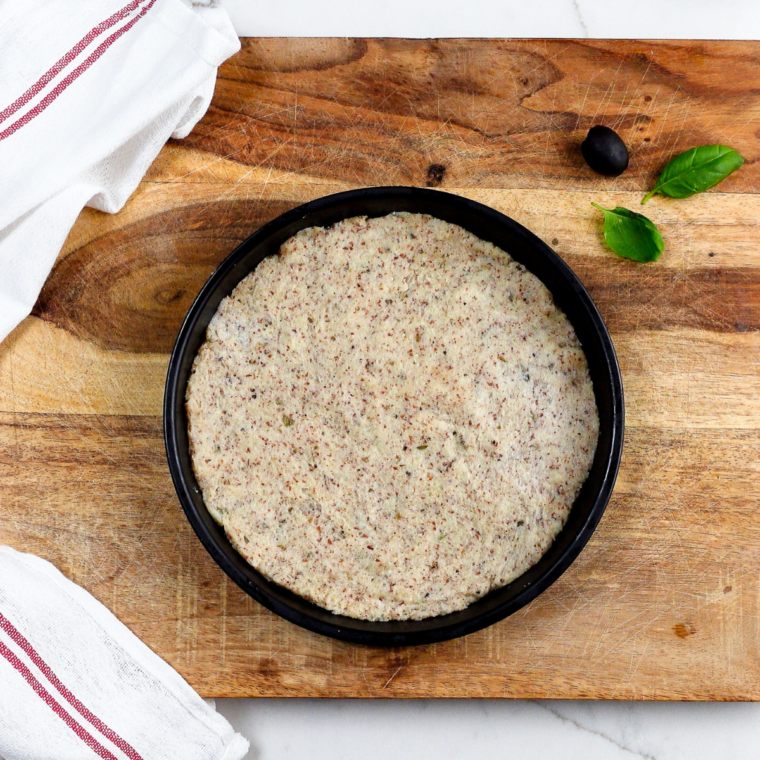 Two ingredient pizza dough rolled thin on a floured wooden surface