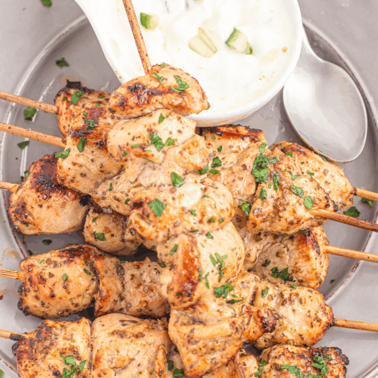 A platter of glazed Air Fryer Chicken Yakitori skewers garnished with sesame seeds and sliced green onions.