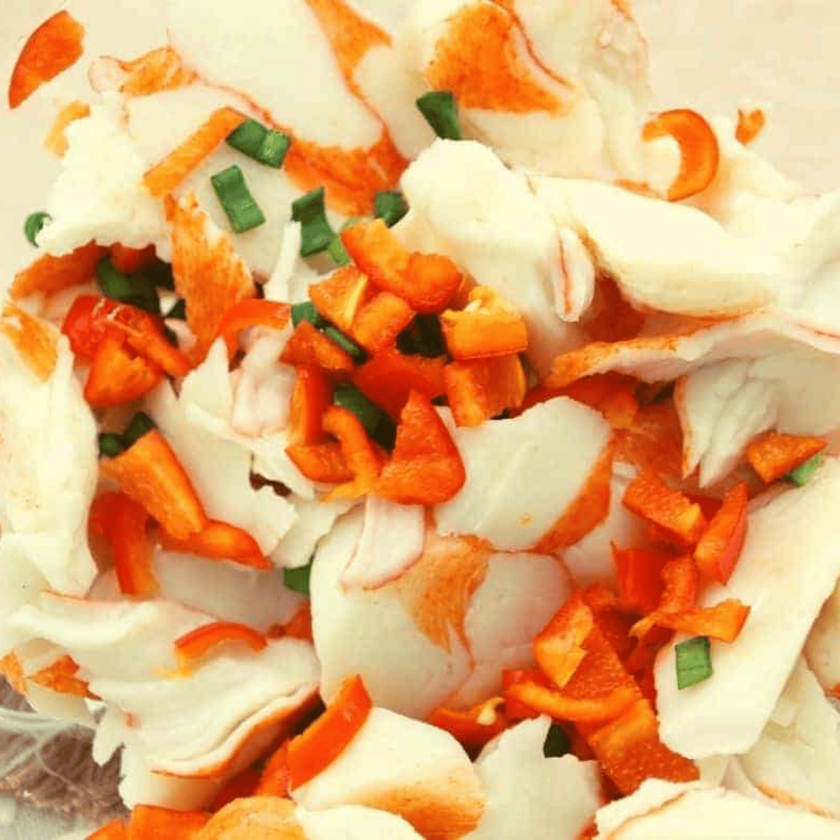 Mixing crab meat with scallions, red bell peppers, salt, and pepper in a bowl.