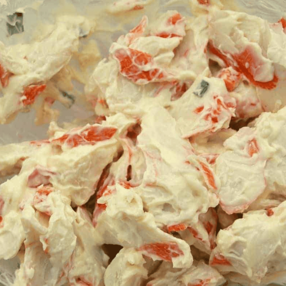 Adding and mixing mayonnaise into the crab and vegetable mixture.