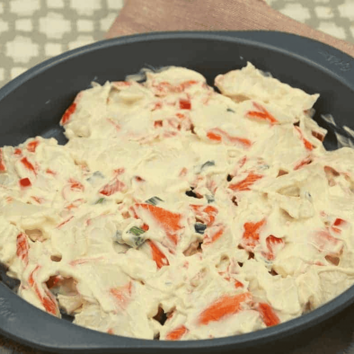 Crab casserole mixture spread in a baking dish, cooking in an air fryer.