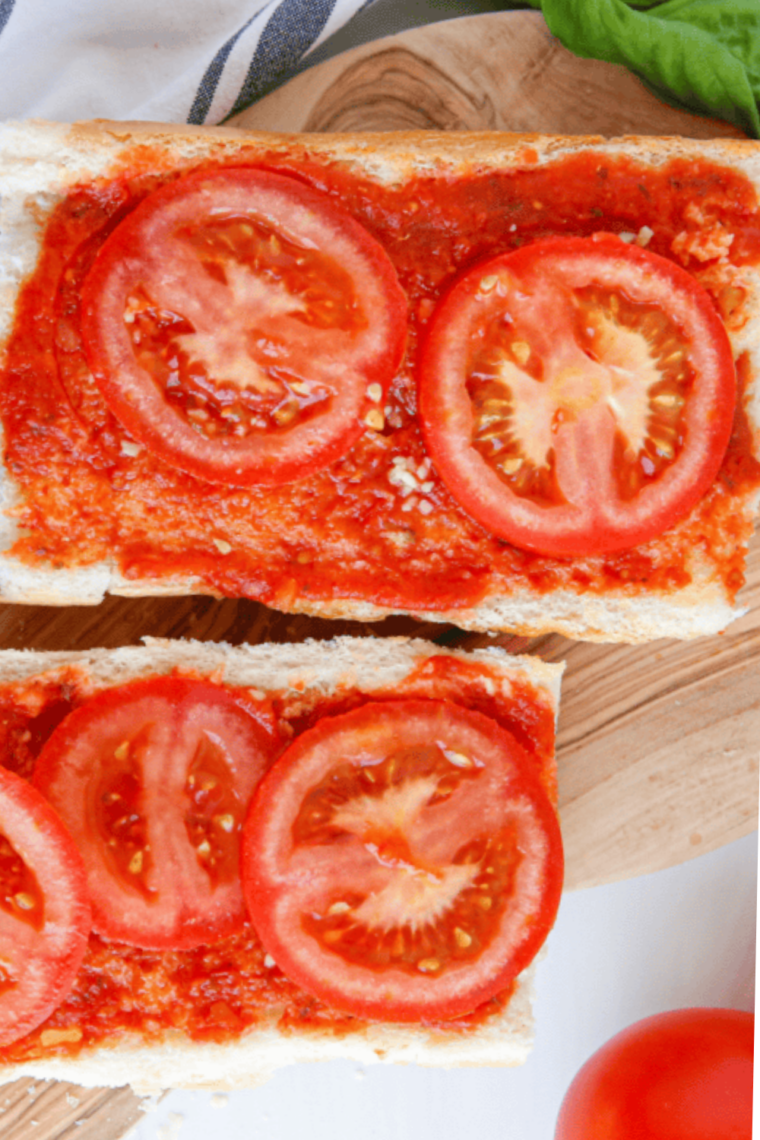 Loaf of French bread sliced in half horizontally on a wooden cutting board for air fryer pizza