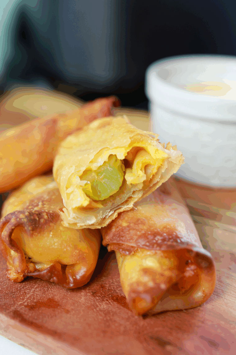 Crispy air fryer pickle egg rolls with melted cheese served with ranch-sriracha dipping sauce.
