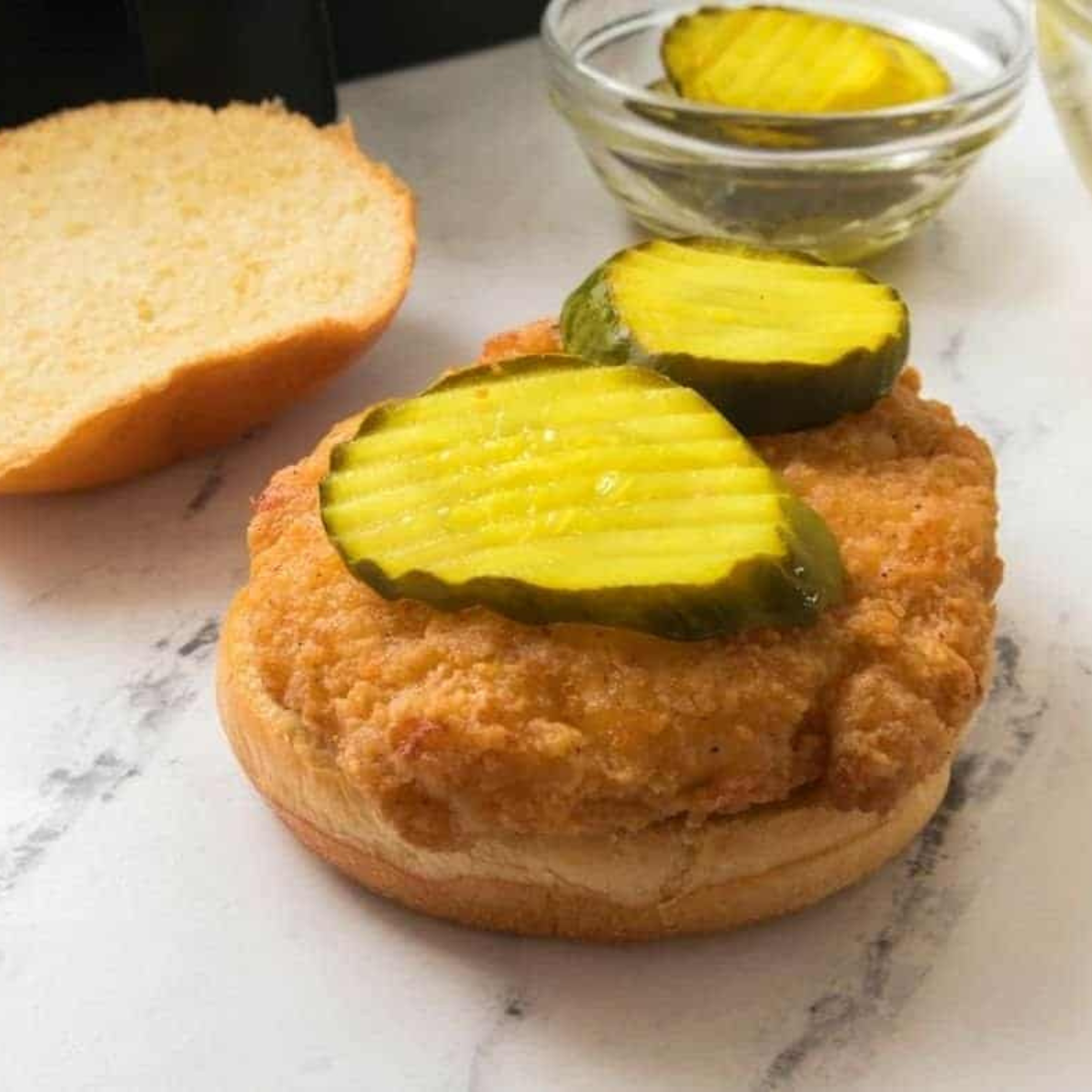 Cooked Red Bag Chicken resting while brioche buns toast in the air fryer basket