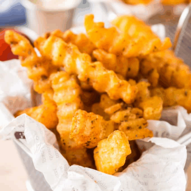 Small bowl of homemade Bojangles-style French fry seasoning with golden crispy fries in the background
