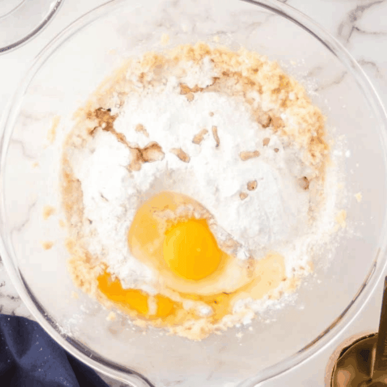 Mixing butter, brown sugar, and sugar in a large bowl, then adding eggs, vanilla, flour, baking powder, salt, and cream to make cake batter.