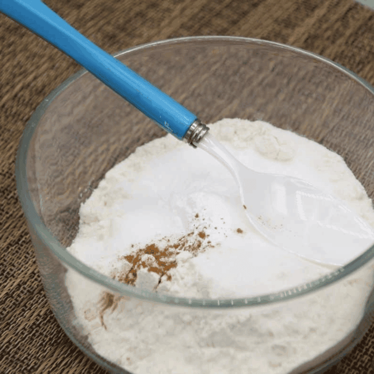 Small mixing bowl with flour, sugar, baking powder, and cinnamon being mixed