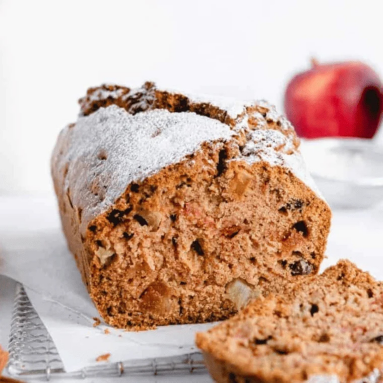 Sliced air fryer apple cranberry bread on a wooden board with fresh cranberries