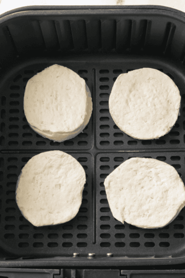 Refrigerated canned biscuits being separated from the package, kept thick and unflattened to ensure even cooking in the air fryer.