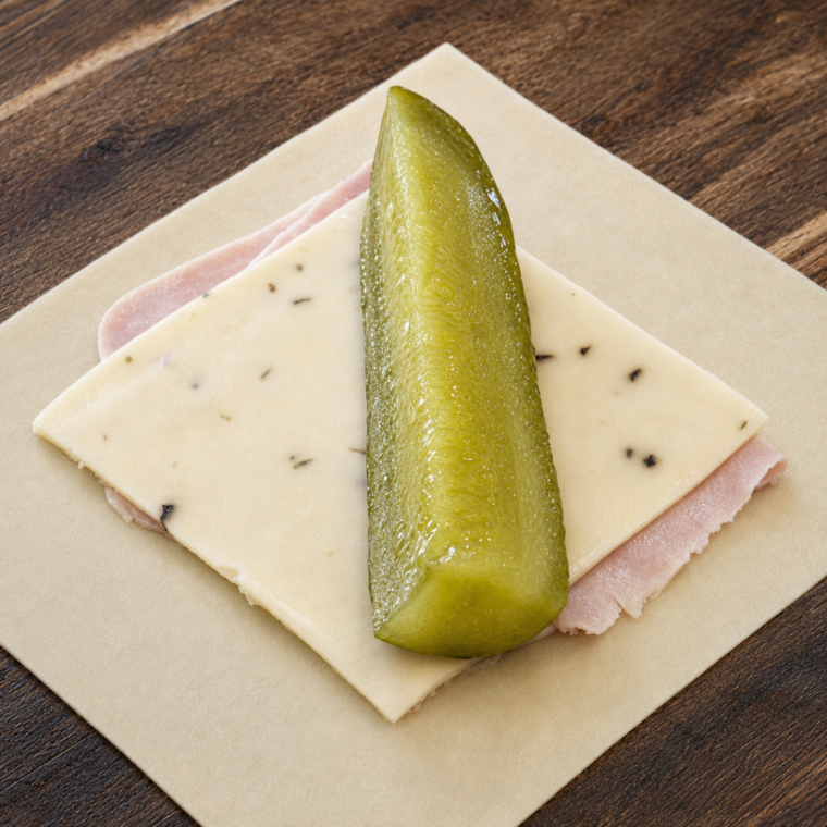 Ham, cheese, and a dill pickle spear layered across an egg roll wrapper