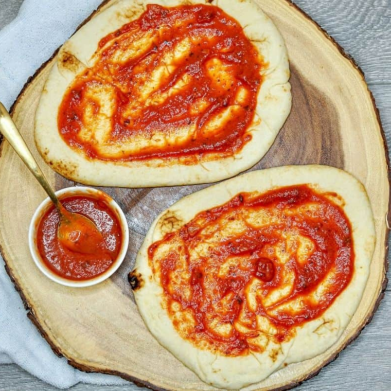 Preheating air fryer and spreading marinara sauce evenly on naan bread edges left exposed