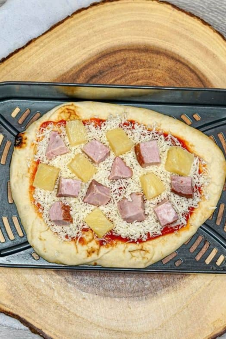 Hawaiian flatbread pizza cooking in air fryer until cheese is melted and edges are golden