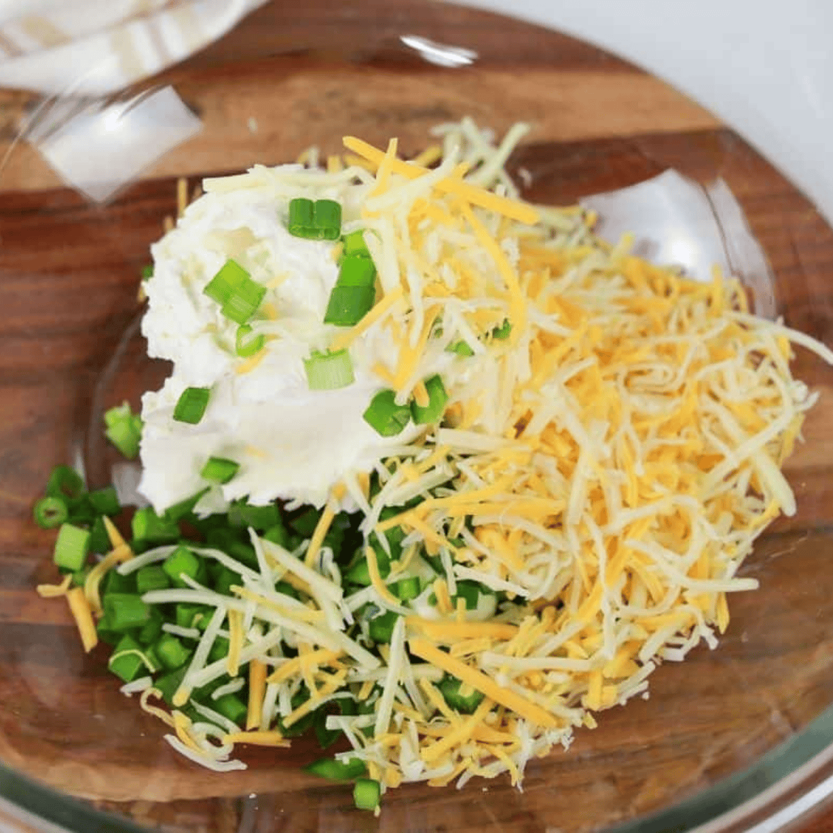 Cream cheese, diced jalapenos, green onions, and shredded cheese in a bowl before mixing