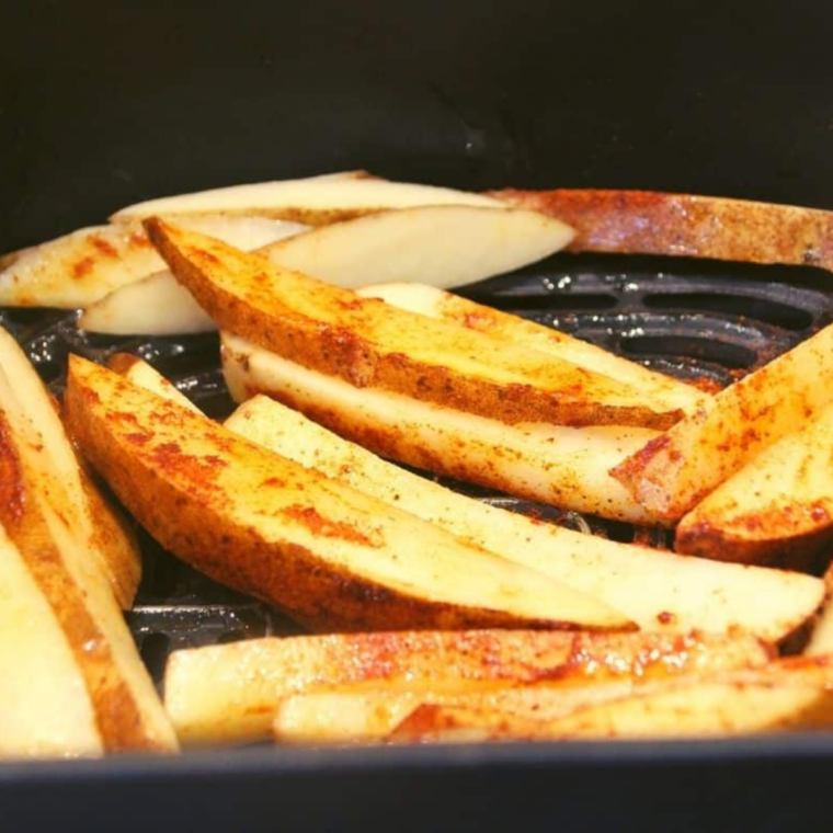Seasoned fries arranged in a single layer inside an air fryer basket